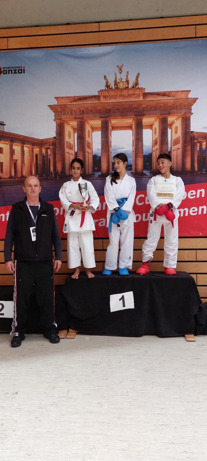 Personen auf einem Podium im Karate-Outfit freuen sich über eine Auszeichnung.
