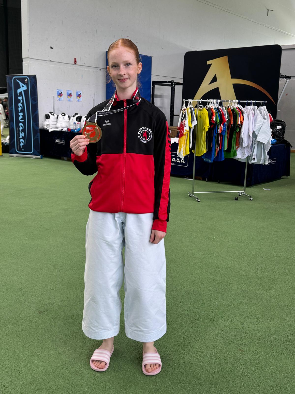 Neutrale Person im rot schwarzen Anzug zeigt Medaille, weiße Hose, Sandalen